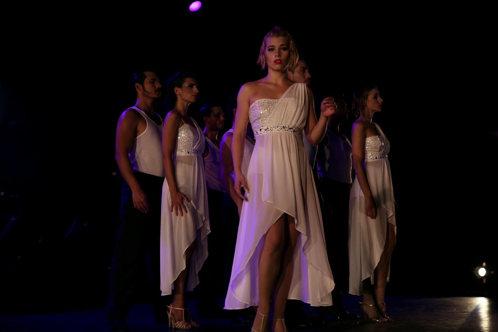Tango Lovers dancers in white dresses under purple stage lighting